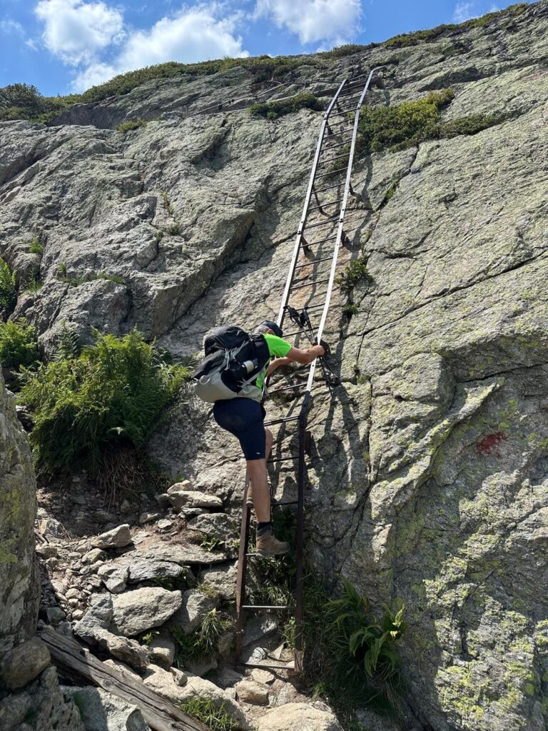 Randonneur sur une échelle dans un passage rocheux du Tour du Mont Blanc