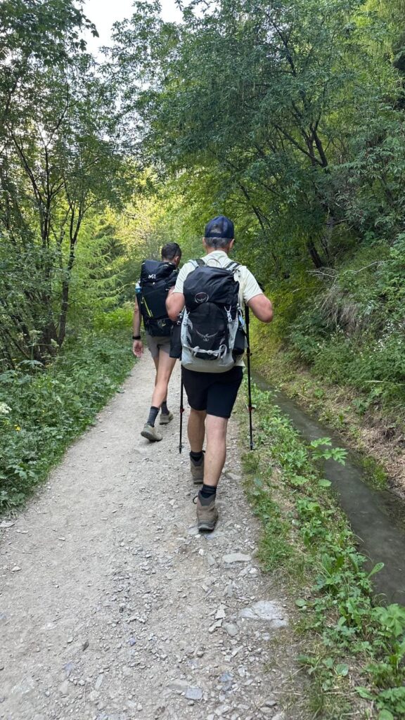 Randonneurs sur un chemin bordé d'un canal d'eau sur le Tour du Mont Blanc