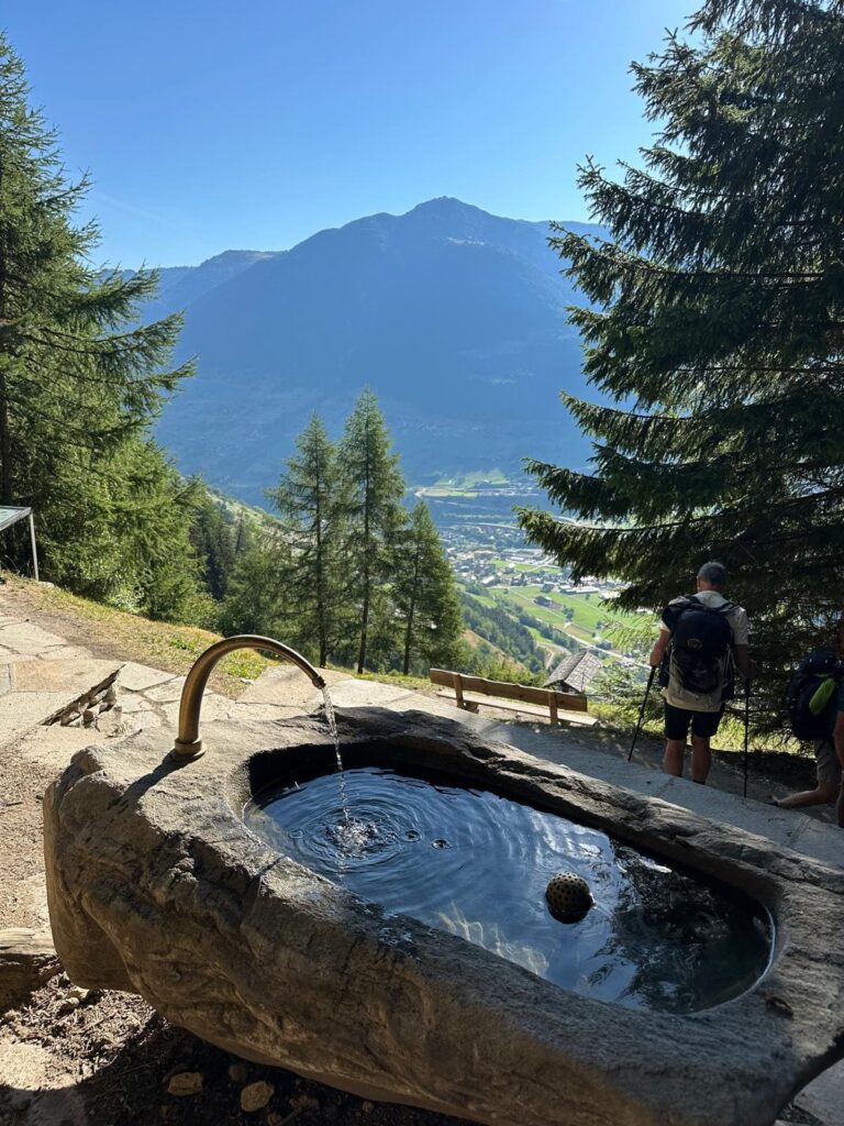 Fontaine en pierre avec vue sur la vallée sur le Tour du Mont Blanc